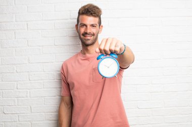 Genç yakışıklı serin adam bir çalar saat tutan