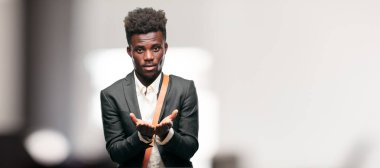 bir nesne veya kavramı her iki el ile gösterilen, ikisi de ileriye dönük memnun bir ifadeyle gülümseyen genç siyah işadamı.