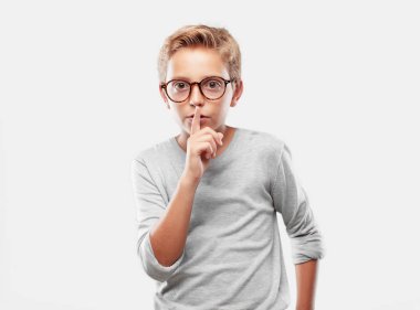 sessizlik isteyen ya da bir sırrı tutmak, ağız, önünde işaret parmağı ile gülümseyen genç sarışın yakışıklı çocuk