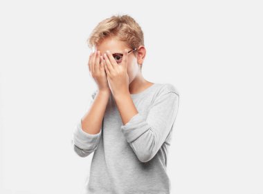 Korkma, korkmuş bir ifade ile genç sarışın yakışıklı çocuk bakmak gözler iki eliyle kapsayan.