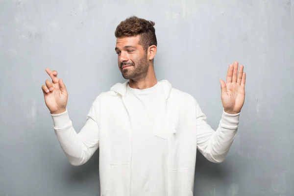 stock image young handsome man smiling confidently while making a sincere promise or oath, solemnly swearing with one hand over heart.