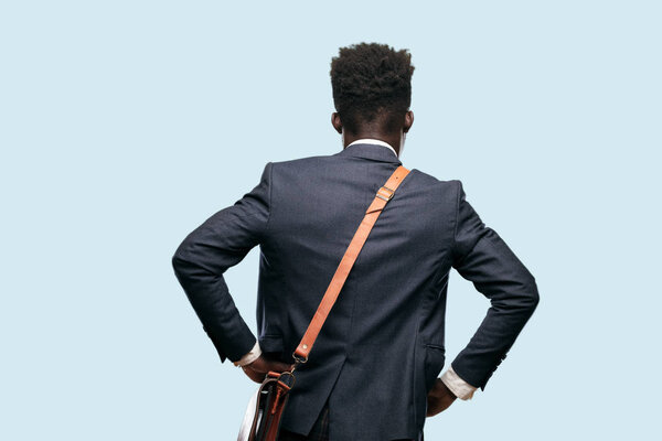 young black businessman back view, both hands on hips with the akimbo pose, probably feeling proud and satisfied.