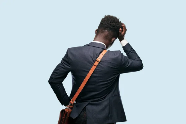 young black businessman back view, hand on hip, pointing with other hand to an object in the distance, somewhere far-off.