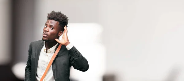 young black businessman paying attention, trying to hear and listen to what is being said, lending an ear.