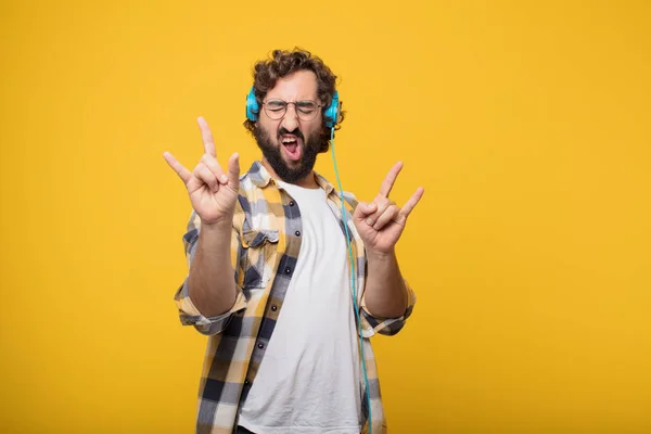 young crazy mad man in fool pose listening music with a headphones