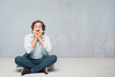 Genç serin sakallı adam yere oturma. Grunge duvar arka plan.