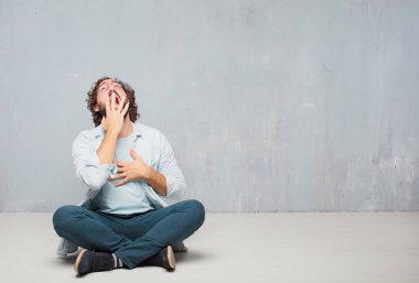 Genç serin sakallı adam yere oturma. Grunge duvar arka plan.