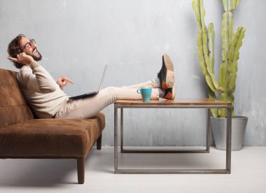 vintage bir oturma odasında bir deri kanepede oturan genç sakallı adam