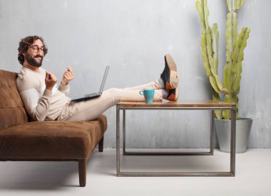 vintage bir oturma odasında bir deri kanepede oturan genç sakallı adam