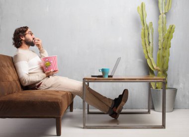 vintage bir oturma odasında bir deri kanepede oturan genç sakallı adam