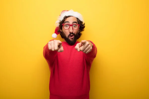 young crazy bearded man wearing red glasses and santa claus hat