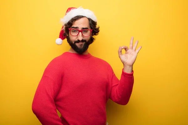 young crazy bearded man wearing red glasses and santa claus hat