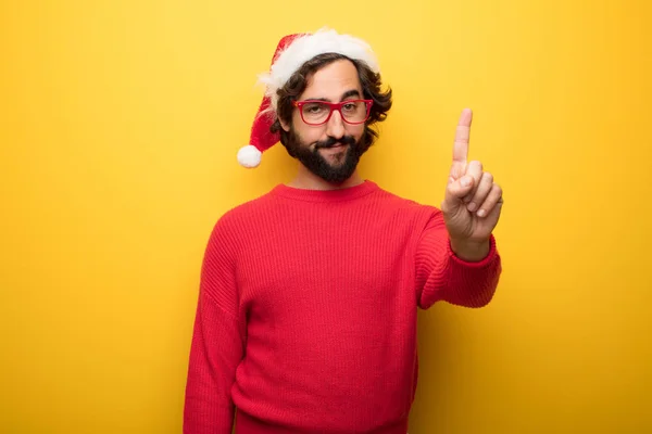 young crazy bearded man wearing red glasses and santa claus hat