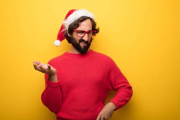 young crazy bearded man wearing red glasses and santa claus hat