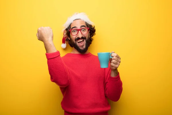 young crazy bearded man wearing red glasses and santa claus hat