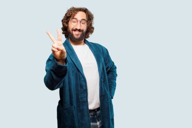 Zafer işareti olan bornoz giymiş genç bir adam.