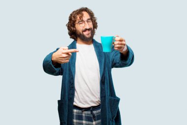 Bornoz giyen genç adam kahve içiyor.