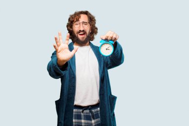 Çalar saati olan bornoz giymiş genç bir adam.