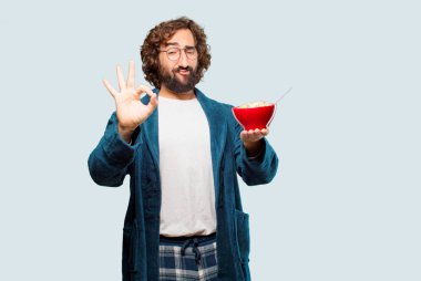 Bornoz giyip kahvaltı kasesi takan genç bir adam.