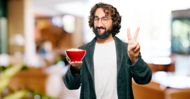 Bornoz giyip kahvaltı kasesi takan genç bir adam.