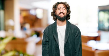 Bornoz giyen genç adam üzgün bir şekilde gece elbisesi giyiyor.