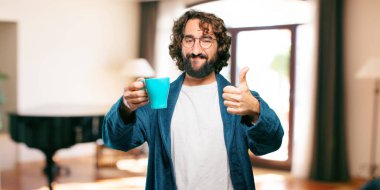 Bornoz giyen genç adam kahve içiyor.