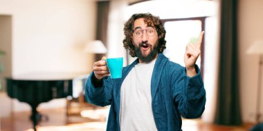 Bornoz giyen genç adam kahve içiyor.