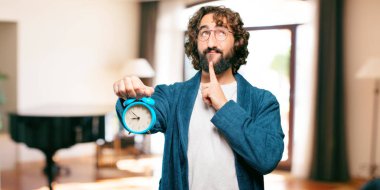 Çalar saati olan bornoz giymiş genç bir adam.