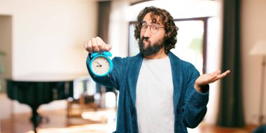 Çalar saati olan bornoz giymiş genç bir adam.