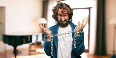 Bornoz giyip prangalı genç bir adam.