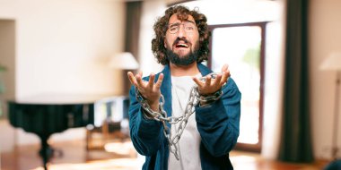 Bornoz giyip prangalı genç bir adam.