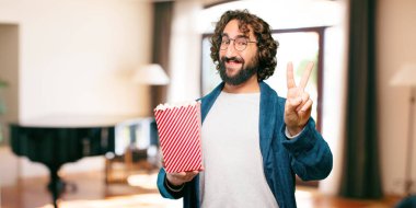 Bornoz giyip, üzerinde patlamış mısır kovası olan genç adam.