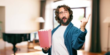 Bornoz giyip, üzerinde patlamış mısır kovası olan genç adam.