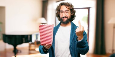 Bornoz giyip, üzerinde patlamış mısır kovası olan genç adam.