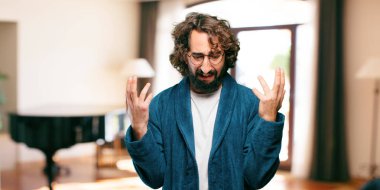 Bornoz giyen genç adam üzgün bir şekilde gece elbisesi giyiyor.