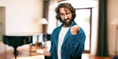 Bornoz giyen genç adam kızgın bir poz veriyor.