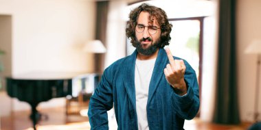 Bornoz giyen genç adam kızgın ve üzgün.