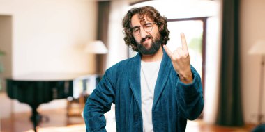 Bornoz giyen genç adam kızgın ve üzgün.