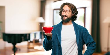 Bornoz giyip kahvaltı kasesi takan genç bir adam.