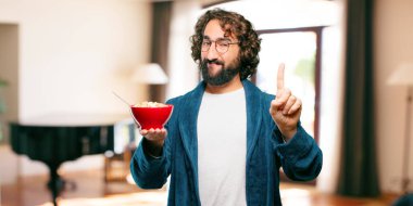 Bornoz giyip kahvaltı kasesi takan genç bir adam.