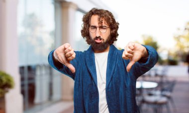 Bornoz giyen genç adam kızgın ve üzgün.