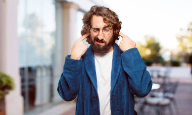 Bornoz giyen genç adam kızgın ve üzgün.