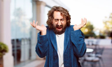 Bornoz giyen genç adam kızgın ve üzgün.