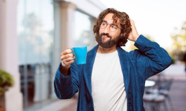 Bornoz giyen genç adam kahve içiyor.