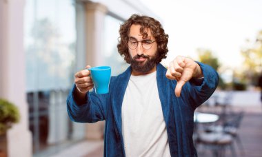 Bornoz giyen genç adam kahve içiyor.