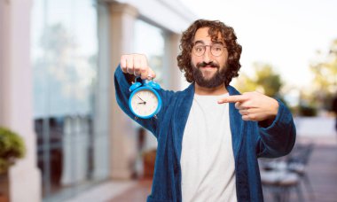 Çalar saati olan bornoz giymiş genç bir adam.