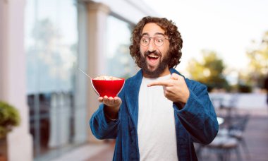 Bornoz giyip kahvaltı kasesi takan genç bir adam.