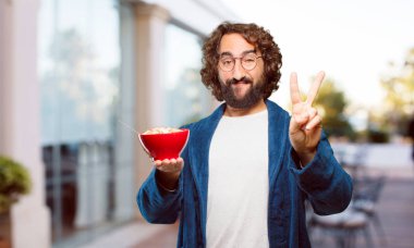 Bornoz giyip kahvaltı kasesi takan genç bir adam.