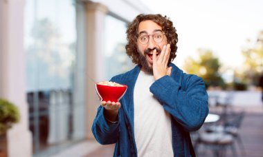 Bornoz giyip kahvaltı kasesi takan genç bir adam.