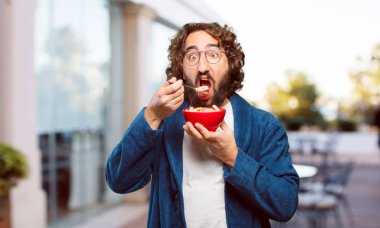 Bornoz giyip kahvaltı kasesi takan genç bir adam.